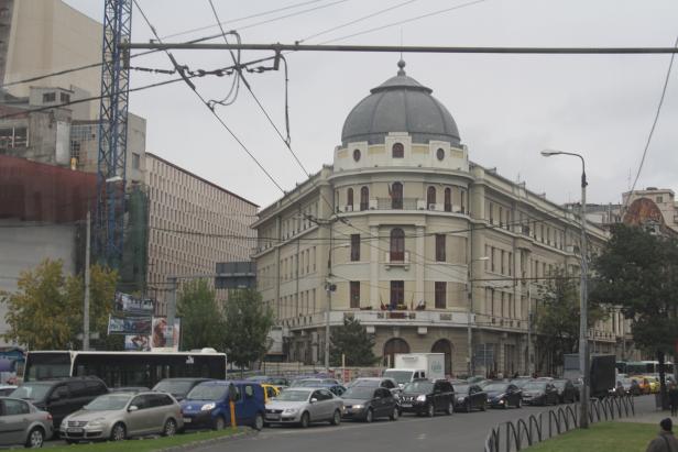 Ein belebtes Stadtbild mit einem markanten Gebäude mit Kuppel und viel Verkehr.