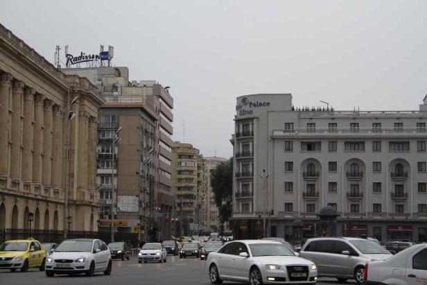 Eine belebte Straße in Bukarest mit dem Radisson Blu und dem Palace Hilton im Hintergrund.