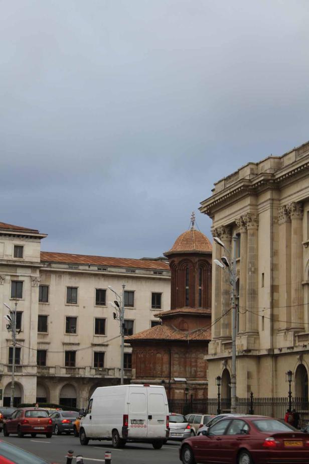 Blick auf die Stavropoleos-Kirche in Bukarest, umgeben von historischen Gebäuden und Straßenverkehr.