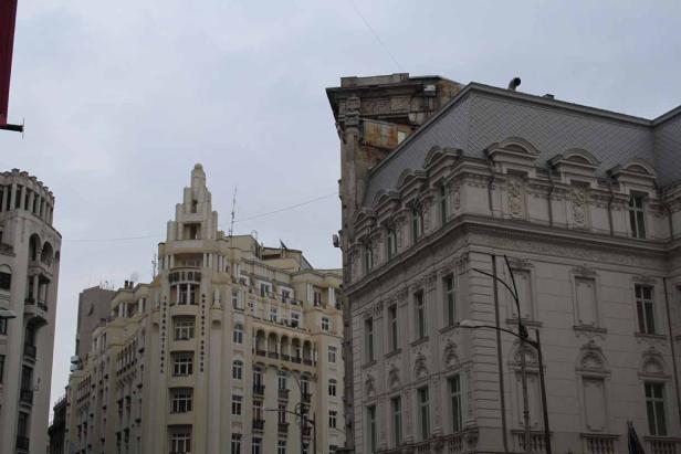 Mehrere hohe Gebäude mit unterschiedlicher Architektur unter einem grauen Himmel.