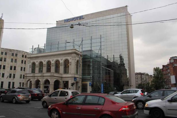 Das Novotel Hotel in Bukarest mit regem Straßenverkehr im Vordergrund.