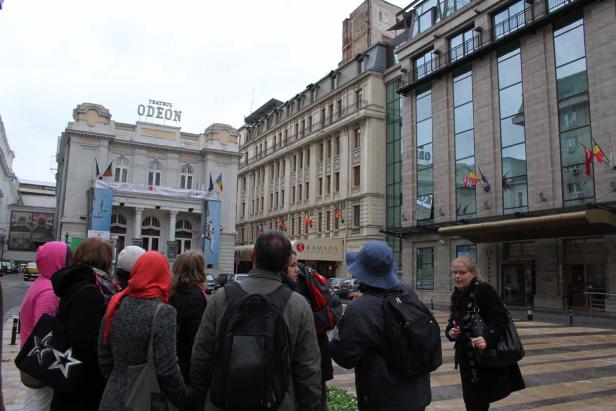 Eine Gruppe von Menschen steht vor dem Teatrul Odeon und dem Ramada Hotel in Bukarest.