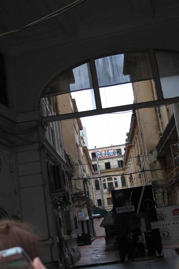 Blick durch einen Torbogen auf eine schmale Gasse zwischen alten Gebäuden.