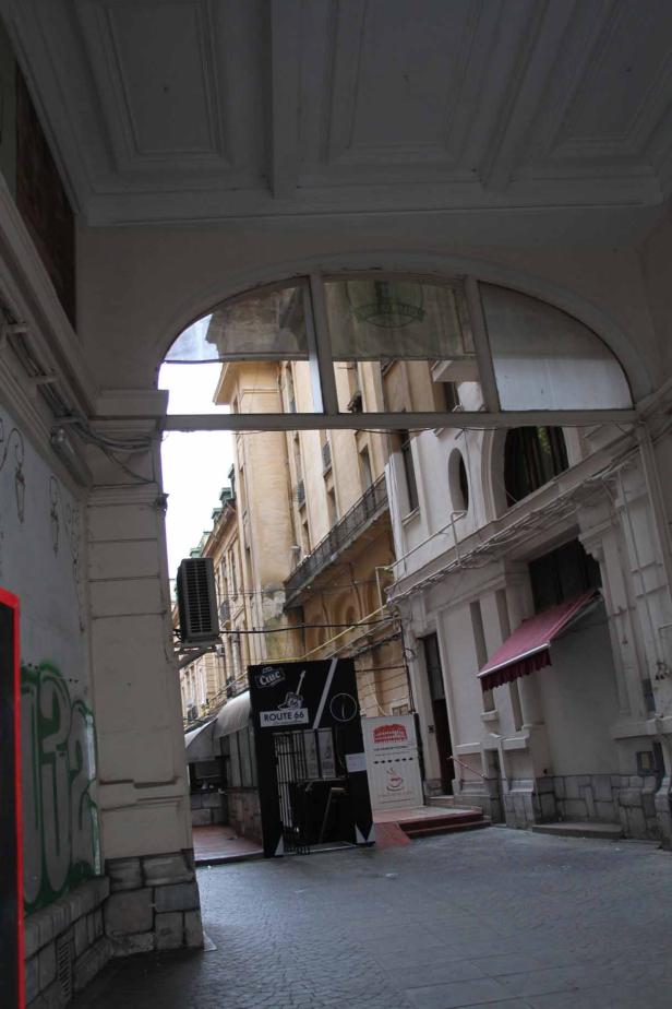 Blick durch einen Torbogen auf eine Gasse mit Restaurants und Geschäften.