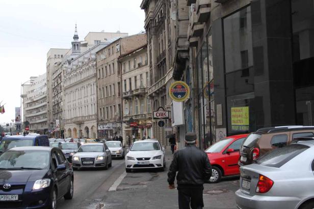 Eine belebte Straße in einer europäischen Stadt mit vielen Autos und alten Gebäuden.