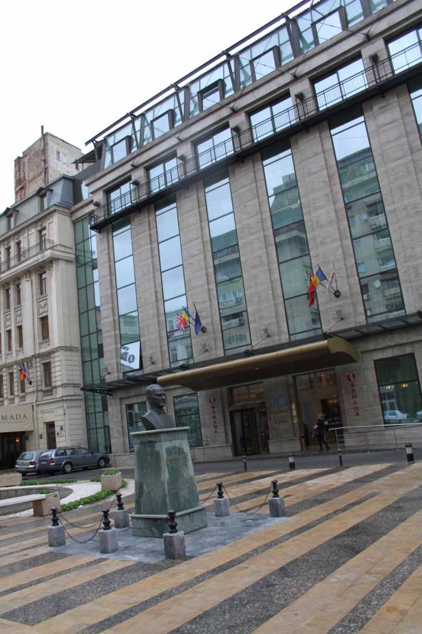Das Ramada Hotel in Bukarest mit einer Büste im Vordergrund.