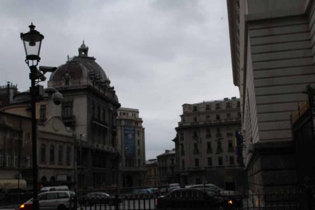 Eine Straßenansicht in Bukarest mit historischen Gebäuden und einem trüben Himmel.