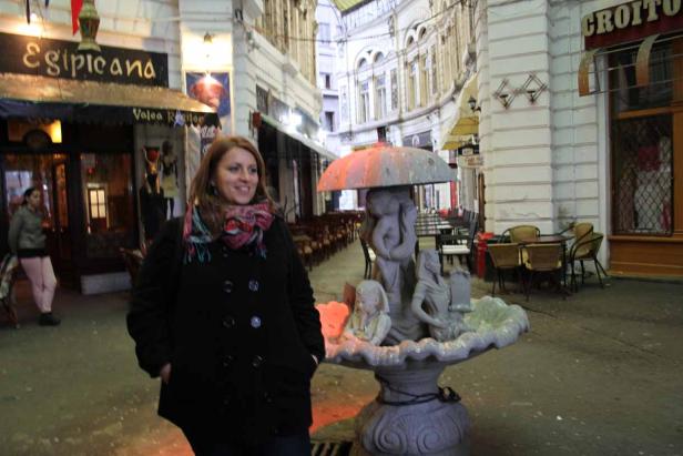 Eine Frau steht vor einem Brunnen in der belebten Straße Pasajul Macca-Vilacrosse in Bukarest.