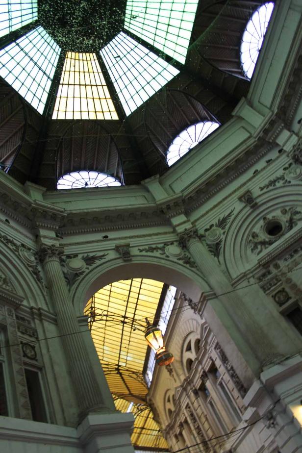 Blick auf die kunstvolle Glaskuppel einer historischen Einkaufspassage.