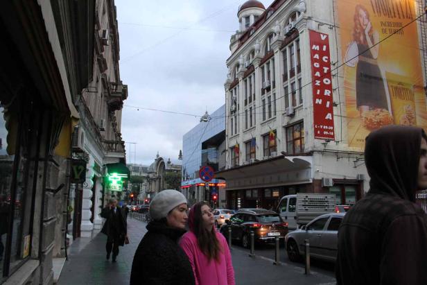 Eine Frau und ein Mädchen stehen auf einem Bürgersteig in einer belebten Stadt.