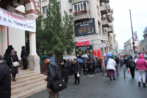 Eine Menschenmenge steht vor einem Gebäude mit Werbeschildern in einer städtischen Umgebung.