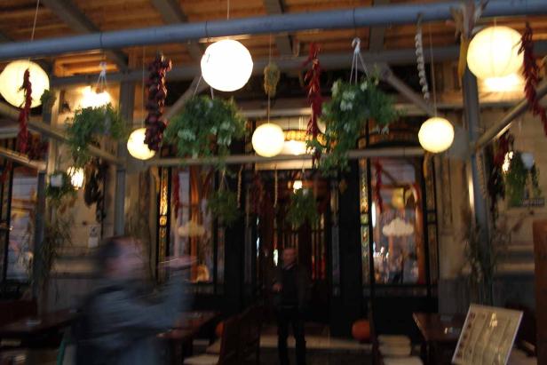 Das Innere eines Restaurants ist mit Lampen, Pflanzen und Dekorationen geschmückt.