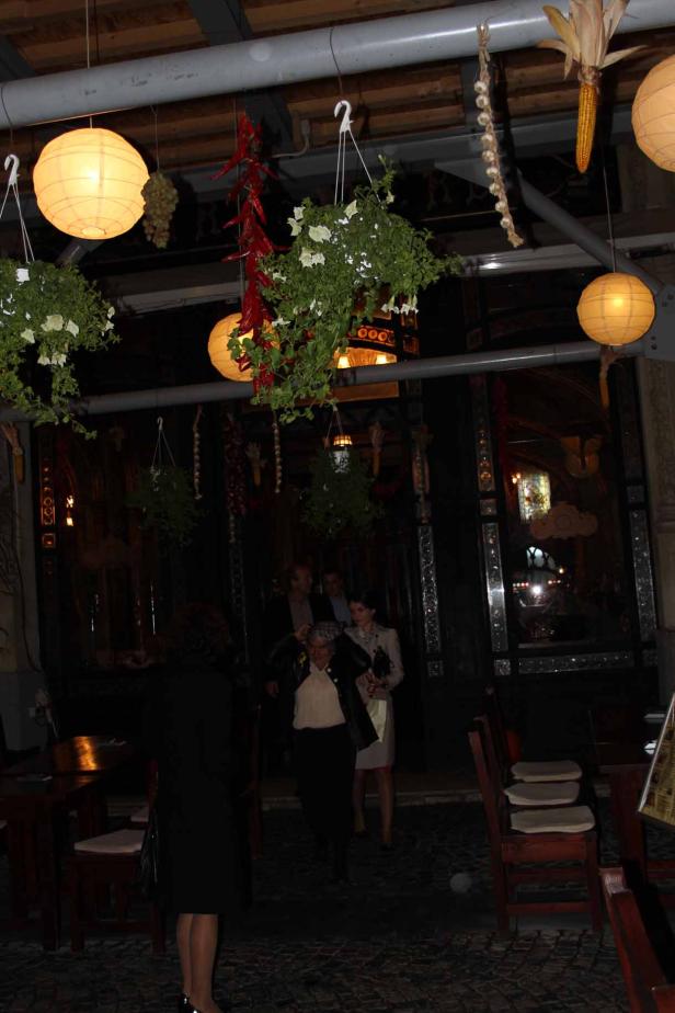 Gäste betreten ein Restaurant, das mit Blumenampeln und Lampions dekoriert ist.