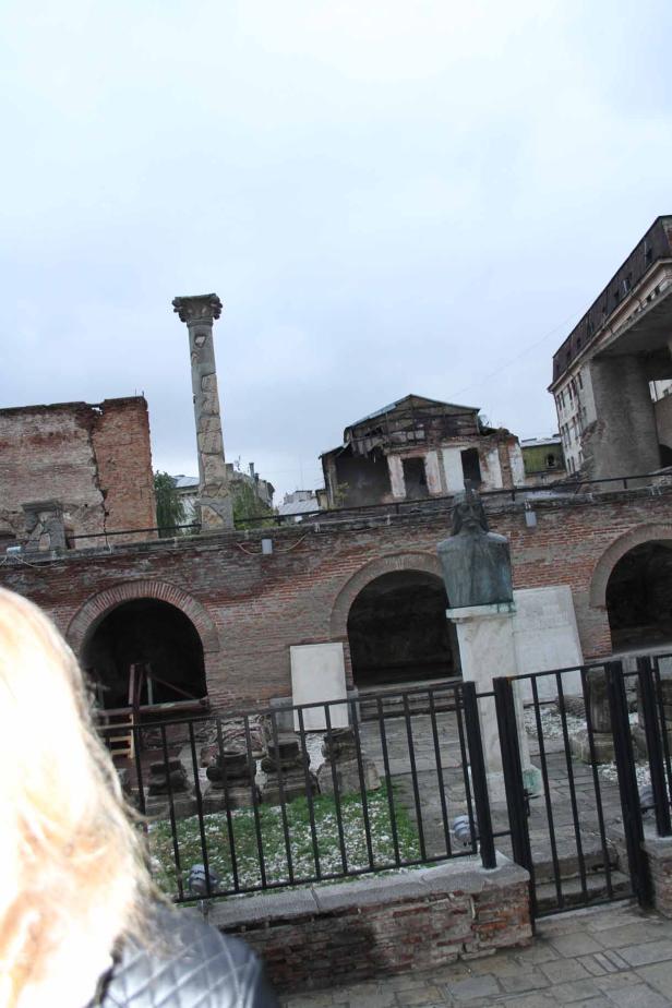 Überreste einer alten römischen Struktur mit einer Säule und einer Statue.