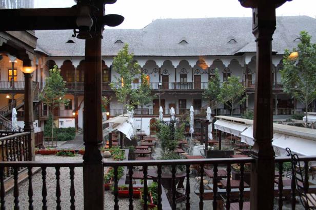 Blick von einem Balkon auf den Innenhof eines historischen Gebäudes mit Restaurant.
