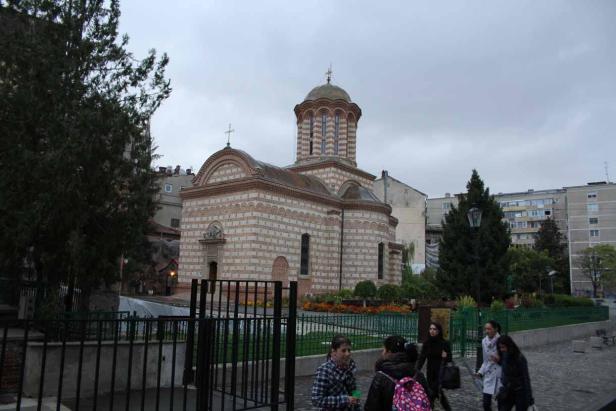 Eine Kirche mit einem Zwiebelturm und Passanten an einem bewölkten Tag.