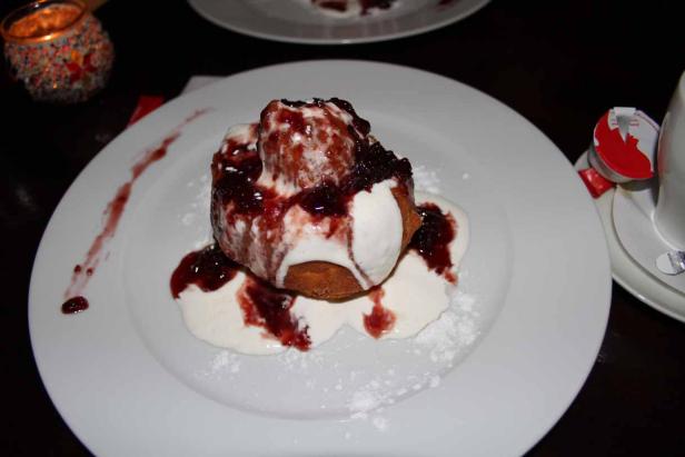 Ein Germknödel mit Vanillesauce und Kirschsoße auf einem Teller.