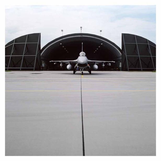 Ein Kampfjet steht vor einem geöffneten Hangar.