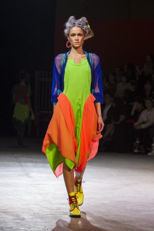 Eine Frau präsentiert ein farbenfrohes Kleidungsstück auf dem Laufsteg.