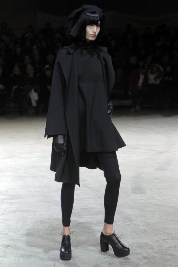 Eine Frau in einem komplett schwarzen Outfit auf einem Laufsteg.