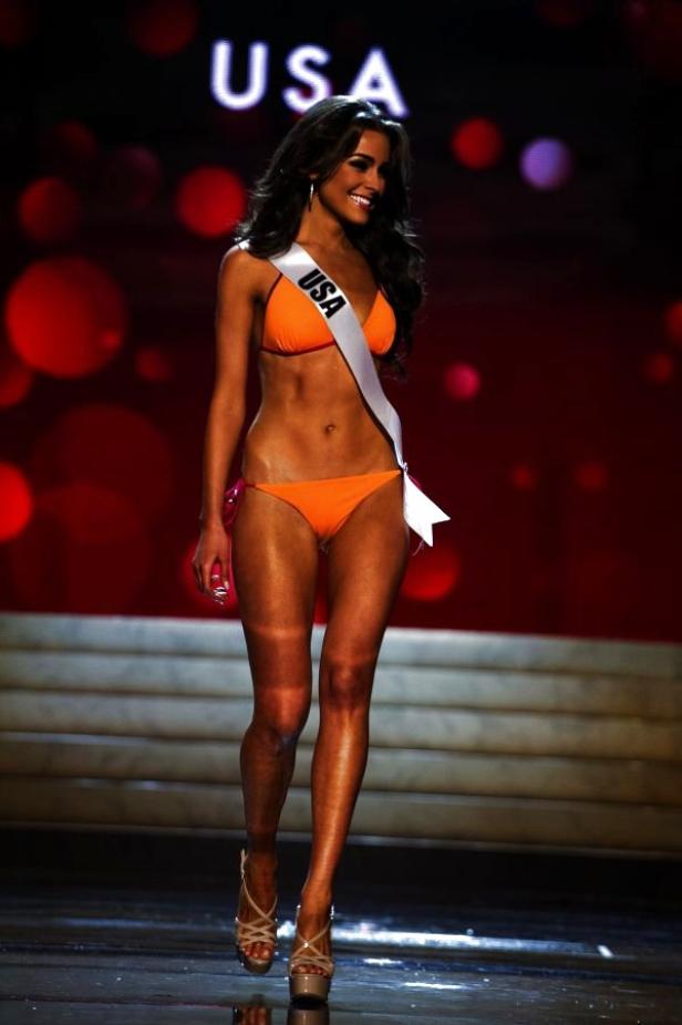 Eine Frau mit einer Schärpe mit der Aufschrift „USA“ in einem orangefarbenen Bikini.
