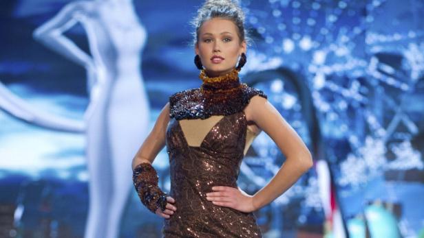 Eine Frau präsentiert ein glitzerndes, braunes Kleid mit passendem Kragen und Armstulpen.