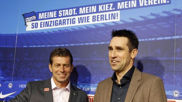 Zwei Männer stehen vor einem Hertha BSC-Banner mit der Aufschrift „Meine Stadt. Mein Kiez. Mein Verein. So einzigartig wie Berlin!“.