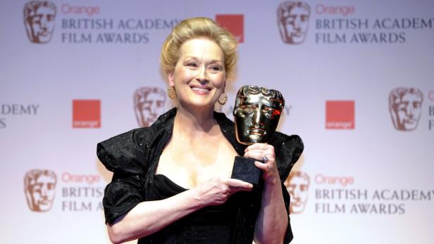 Meryl Streep hält eine goldene BAFTA-Maske in der Hand und lächelt.