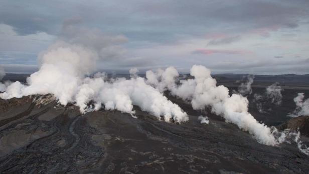 Dampf steigt aus einer vulkanischen Landschaft auf Island auf.