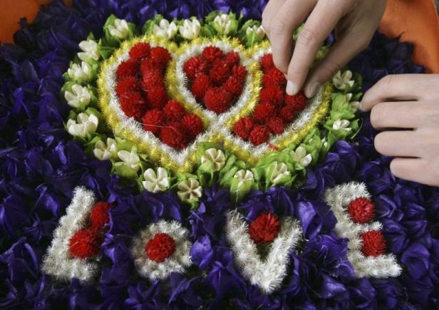Hände ordnen ein Blumenmuster mit der Aufschrift „Love“.