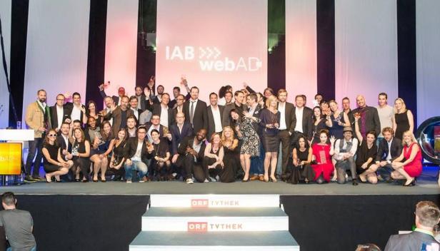 Eine große Gruppe von Menschen posiert auf einer Bühne für ein Foto bei der IAB webAD Preisverleihung.