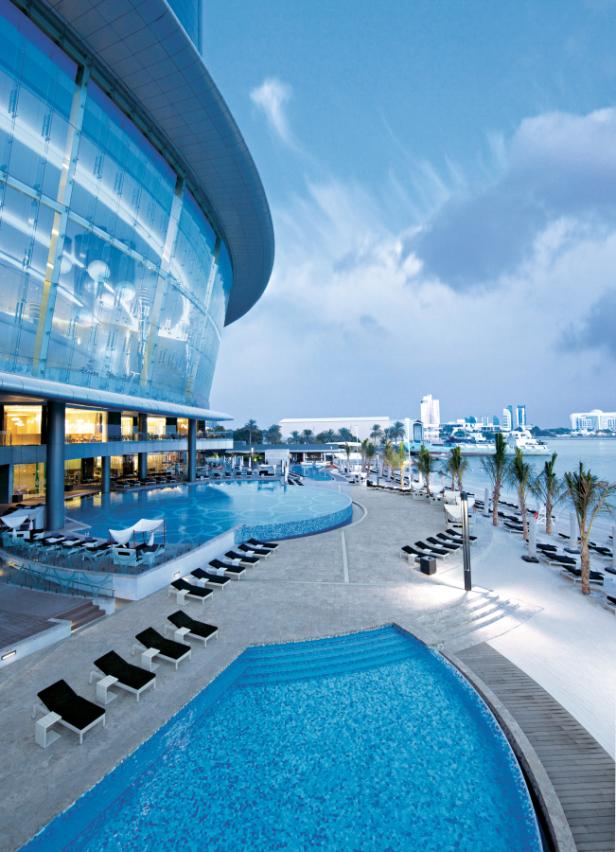 Ein Hotel mit mehreren Pools und Liegestühlen am Strand.