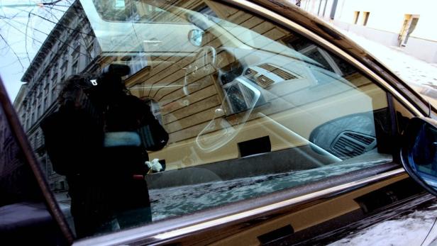 Die Spiegelung eines Gebäudes und einer Person im Fenster eines Autos.