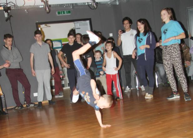 Ein Junge macht einen Handstand vor einer Gruppe von Zuschauern.