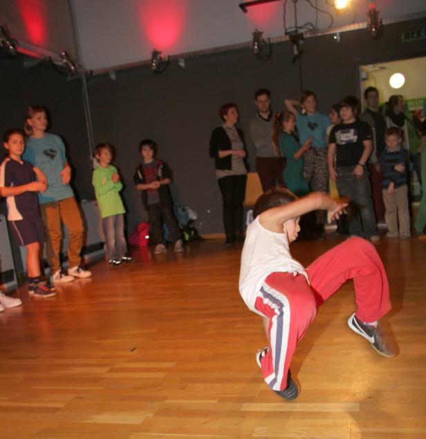 Ein Junge tanzt Breakdance vor einer Gruppe von Zuschauern.