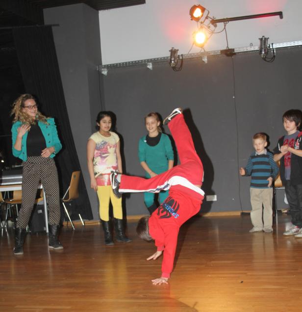 Ein Junge macht einen Handstand vor einer Gruppe von Kindern und einer Frau.