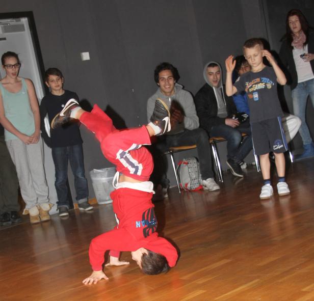 Ein Junge macht einen Handstand vor einer Gruppe von Zuschauern.