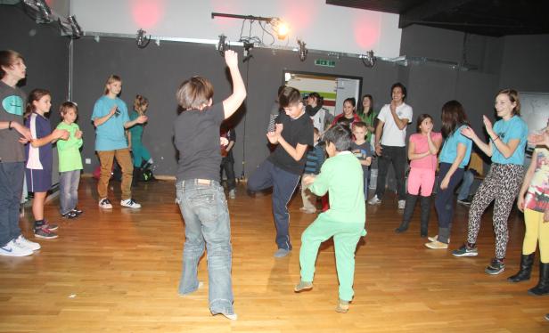 Eine Gruppe von Kindern tanzt und klatscht in einem Tanzstudio.