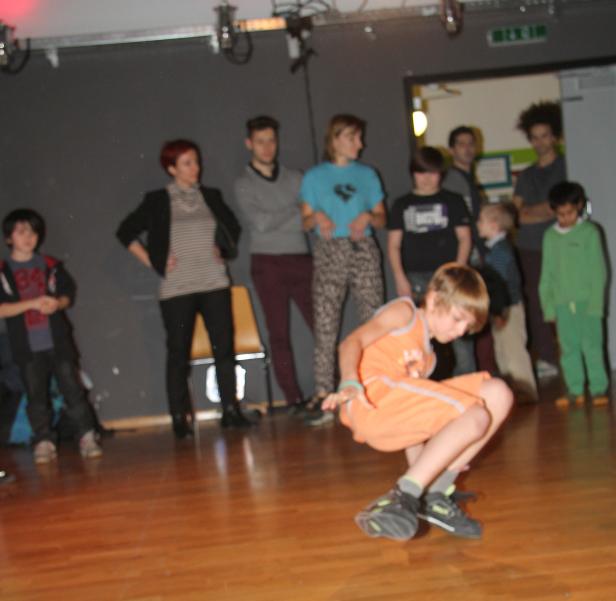 Ein Junge tanzt Breakdance vor einer Gruppe von Zuschauern.