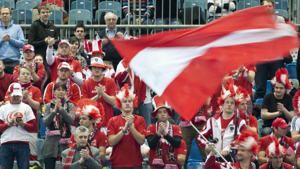 Eine Gruppe österreichischer Fans feuert ihr Team mit einer großen rot-weißen Flagge an.