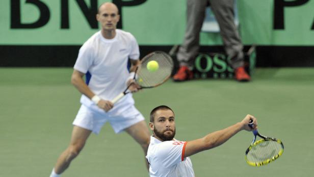 Zwei Tennisspieler während eines Matches auf einem grünen Platz.