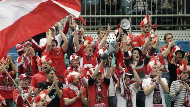 Eine Gruppe österreichischer Fans feuert ihr Team mit Fahnen und Megaphonen an.
