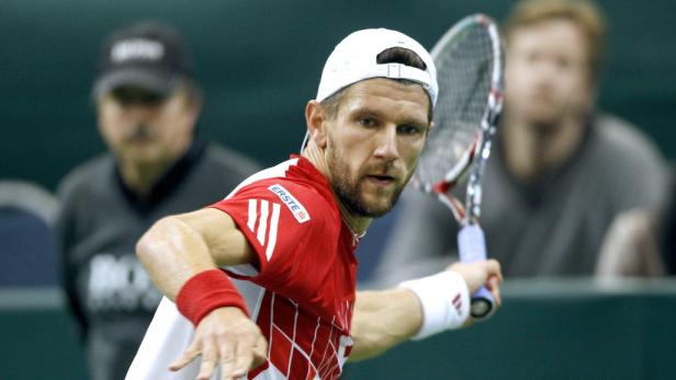 Ein Tennisspieler mit weißer Kappe schlägt einen Ball.