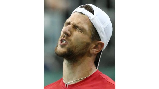 Ein Mann mit weißer Kappe und rotem Hemd blickt mit zusammengekniffenen Augen nach oben.