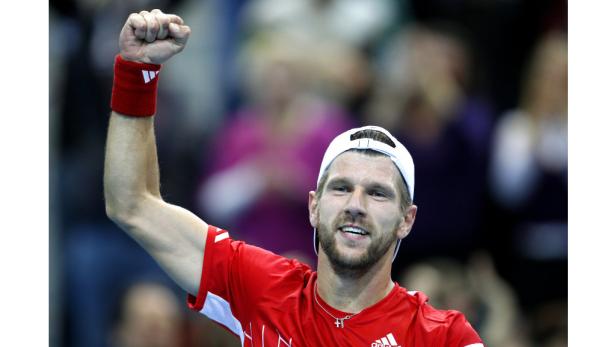 Ein Tennisspieler in rotem Hemd und weißer Kappe jubelt mit erhobener Faust.