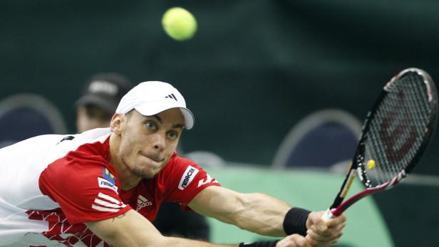 Ein Tennisspieler schlägt einen Ball mit seinem Schläger.