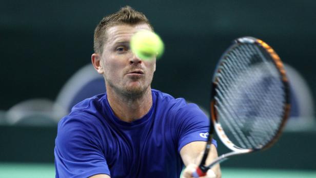 Ein Tennisspieler schlägt einen Ball mit seinem Schläger.