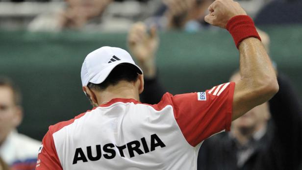 Ein Tennisspieler mit dem Schriftzug „AUSTRIA“ auf dem Rücken jubelt mit erhobenem Arm.