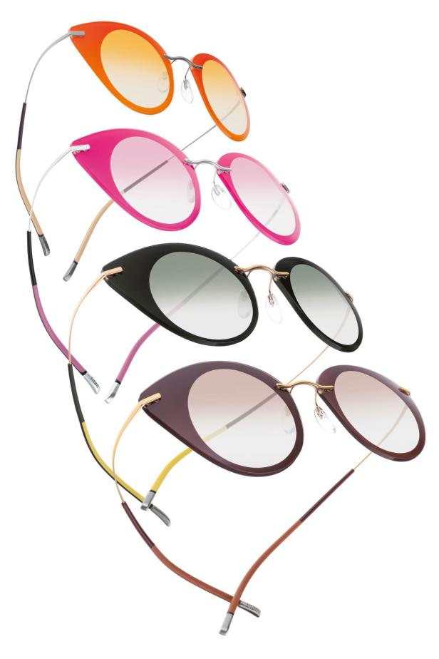 Mehrere randlose Brillen in Orange, Pink, Schwarz und Braun sind übereinander gestapelt.