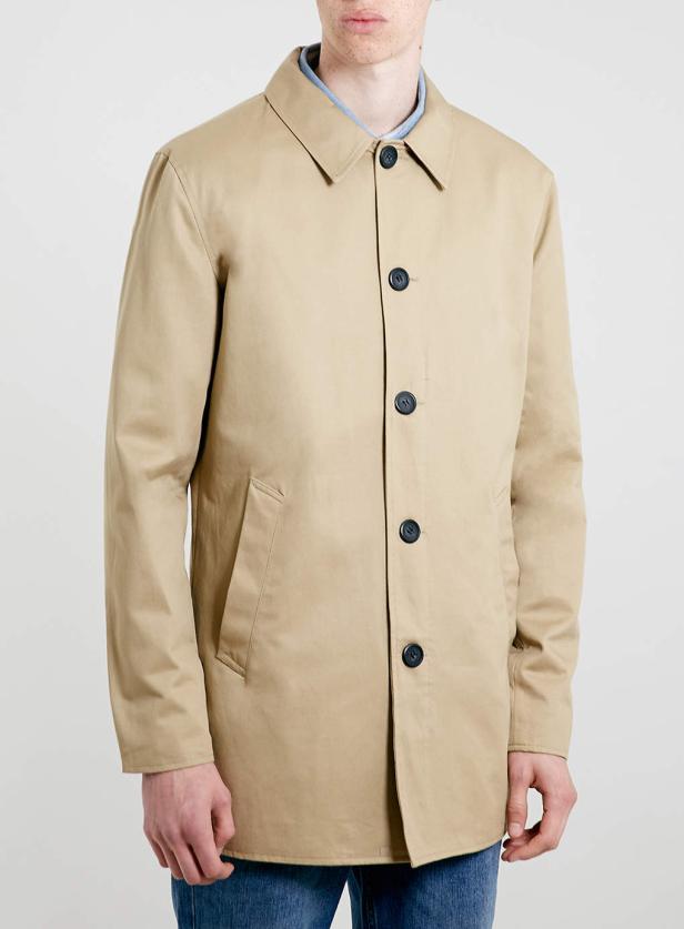 Ein Mann trägt einen beigen Kurzmantel mit dunklen Knöpfen.